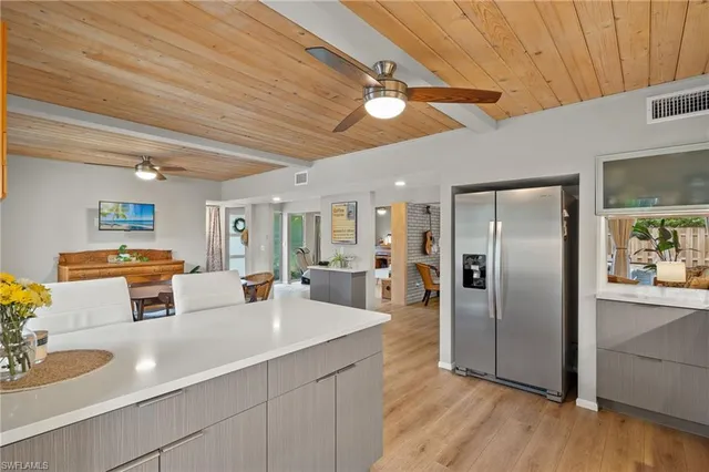 a kitchen with stainless steel appliances granite countertop a refrigerator a sink dishwasher and a stove with wooden floor