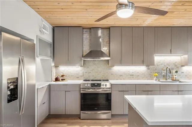 a kitchen with stainless steel appliances granite countertop a sink a stove and refrigerator