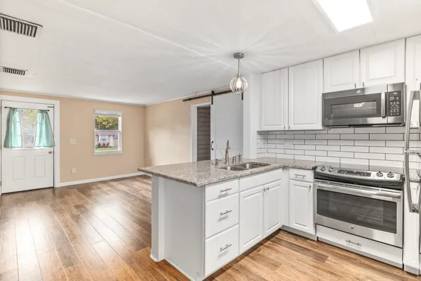 a kitchen with stainless steel appliances granite countertop a stove a sink and a microwave