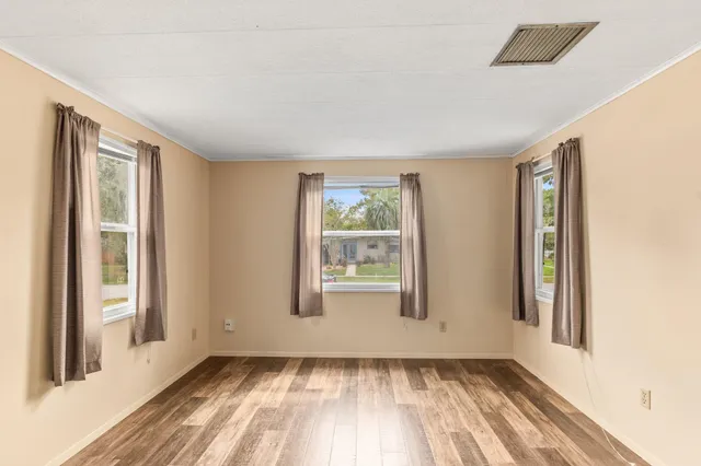 a view of an empty room with a window and wooden floor