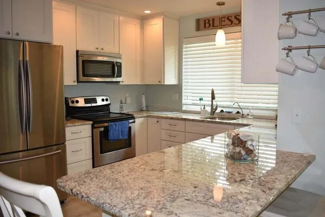 a kitchen with stainless steel appliances granite countertop a sink a stove and a refrigerator