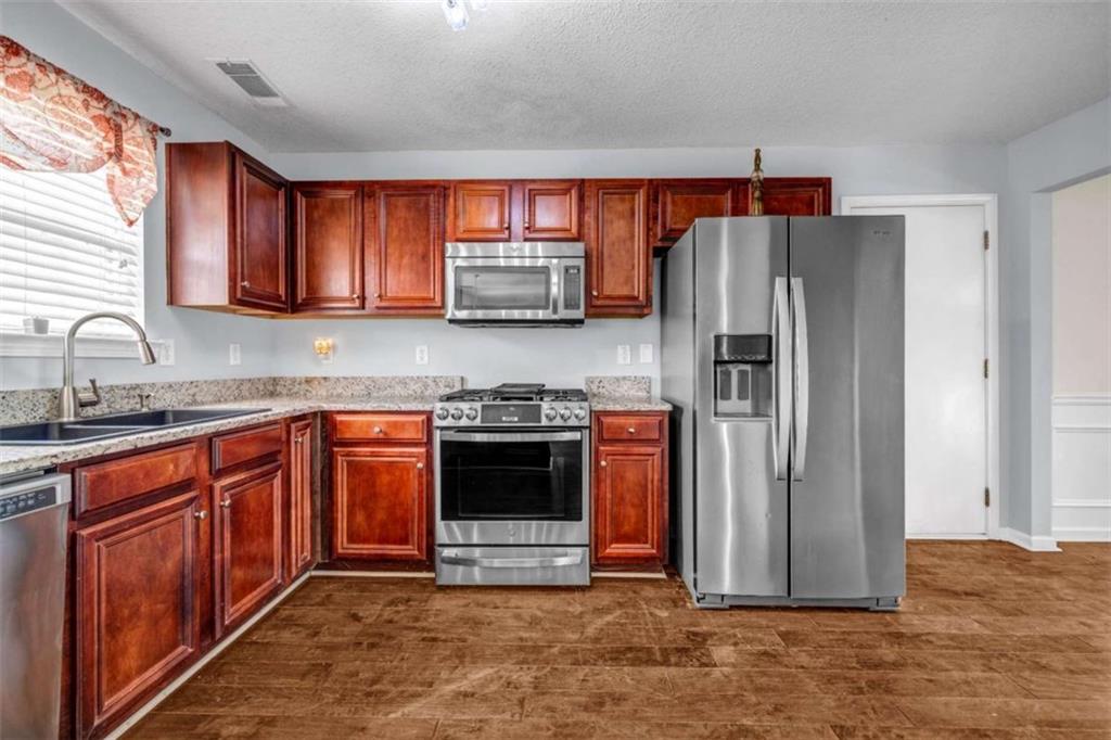 1903 Cobblestone Court Conyers, GA 30012 - Photo 3 of 30 a kitchen with stainless steel appliances granite countertop a refrigerator sink and stove