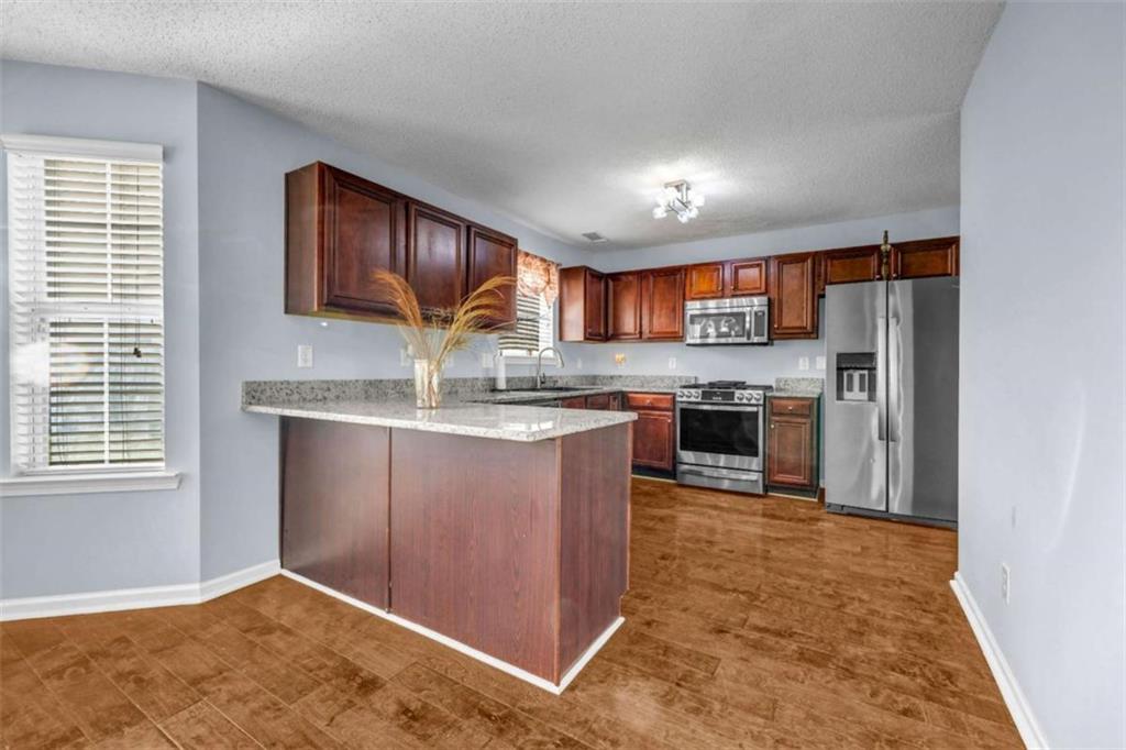 1903 Cobblestone Court Conyers, GA 30012 - Photo 6 of 30 a kitchen with stainless steel appliances granite countertop a stove top oven a sink and a refrigerator