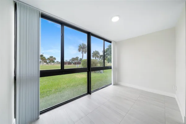 a view of an empty room with wooden floor and floor to ceiling window