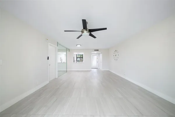 an empty room with wooden floor ceiling fan and windows