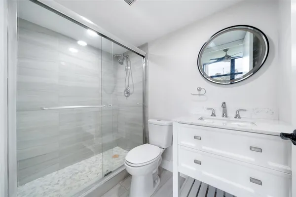 a bathroom with a toilet a sink a mirror and a shower