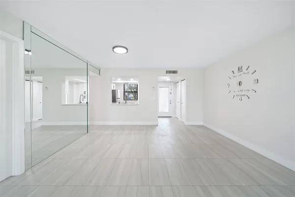 a view of an empty room with window and wooden floor