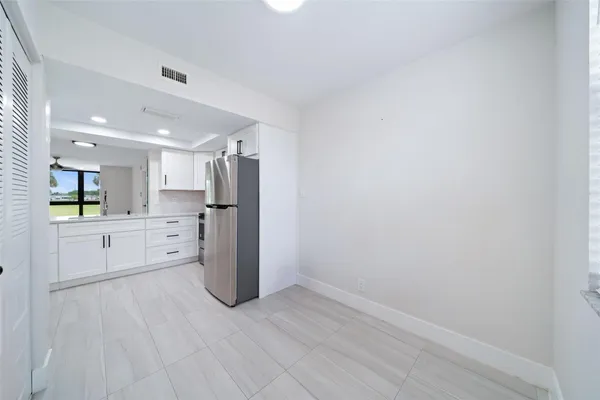 a view of a kitchen with refrigerator and white cabinets