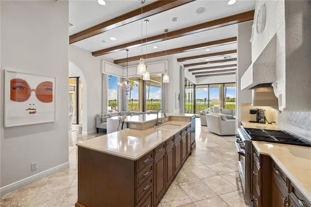 a large kitchen with kitchen island a sink stainless steel appliances wooden floor and a large window