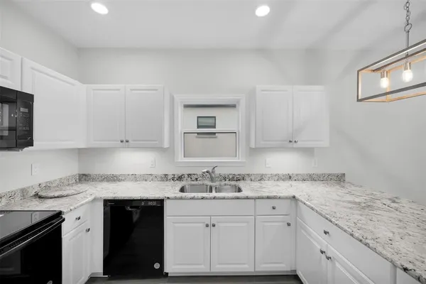 a kitchen with granite countertop stainless steel appliances white cabinets granite counter tops and a wooden floors