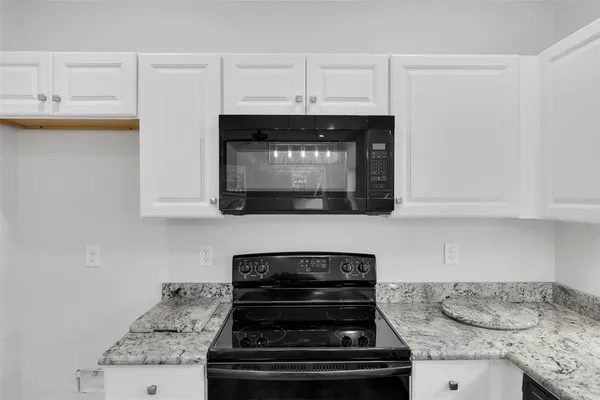 a kitchen with granite countertop a stove and a microwave