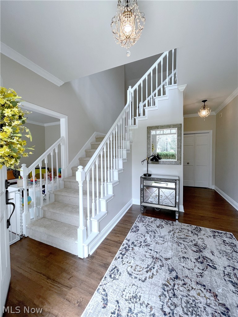 718 Sunridge Road Fairlawn, OH 44333 - Photo 3 of 49 Stairway with crown molding, an inviting chandelier, and dark wood-type flooring