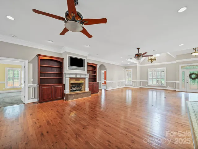 a view of a livingroom with a ceiling fan wooden floor and window
