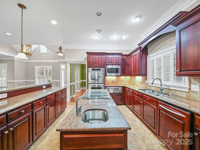 a large kitchen with stainless steel appliances granite countertop a stove a sink and a oven