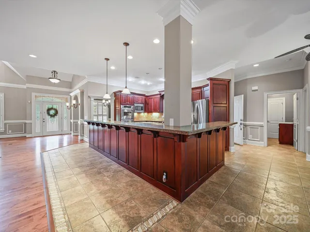 a large kitchen with stainless steel appliances kitchen island granite countertop a table and chairs
