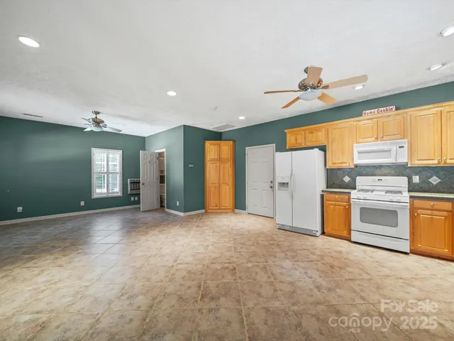 a view of an empty room with a window and kitchen view