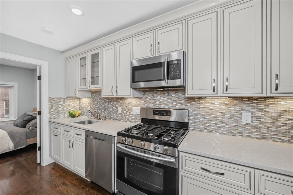1880 Beacon Street, Unit 6 Brookline, MA 02445 - Photo 6 of 18 a kitchen with granite countertop white cabinets and stainless steel appliances