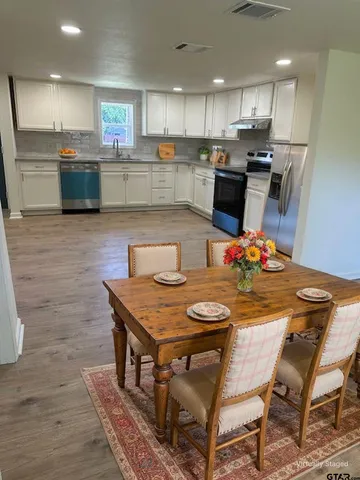 a kitchen with stainless steel appliances kitchen island granite countertop a table chairs and a refrigerator
