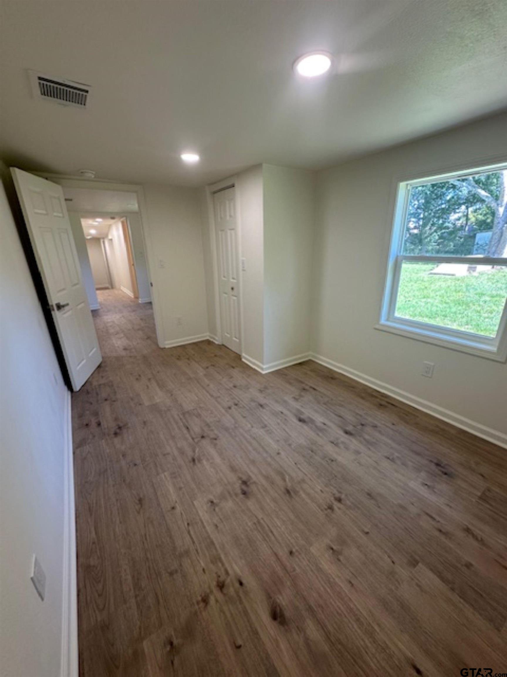 149 East Iowa Street Van, TX 75790 - Photo 10 of 17 an empty room with wooden floor and windows