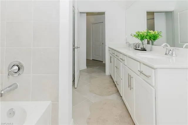 a bathroom with a double vanity sink a large mirror and a bathtub