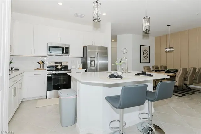 a kitchen with stainless steel appliances a stove a sink a dining table and chairs