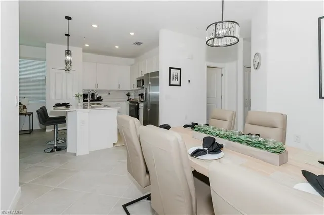 a kitchen with stainless steel appliances kitchen island granite countertop a table chairs stove and white cabinets