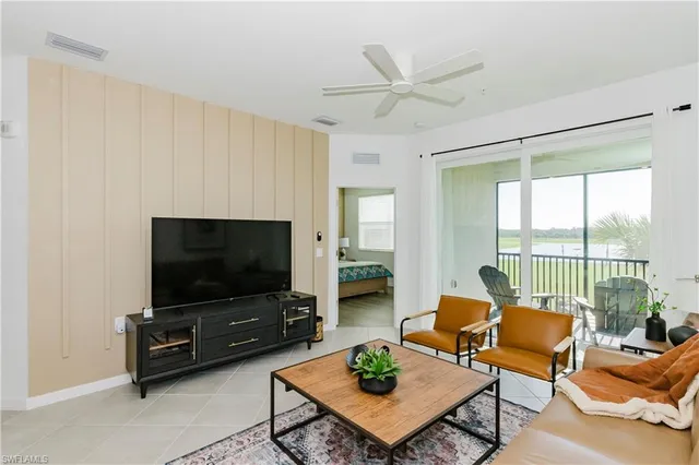 a living room with furniture a flat screen tv and a large window