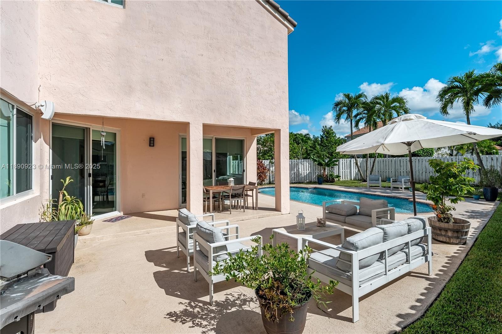 925 Briar Ridge Road Weston, FL 33327 - Photo 26 of 30 a view of a patio with couches table and chairs under an umbrella with potted plants