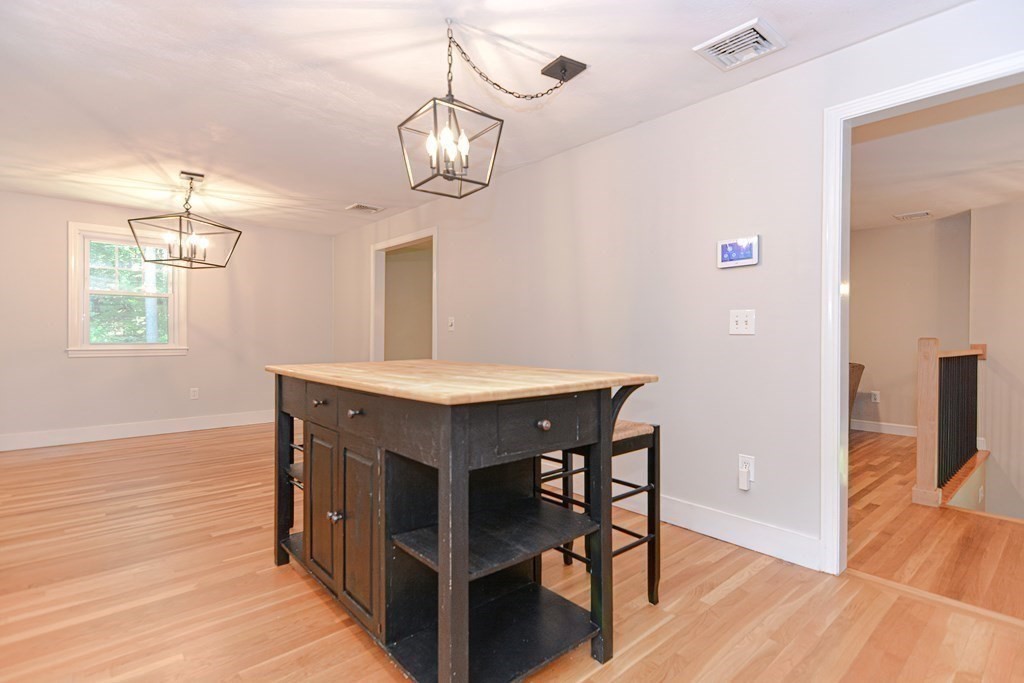 137 Howard Street Northborough, MA 01532 - Photo 13 of 41 a dining room with wooden floor a chandelier a wooden table and chairs