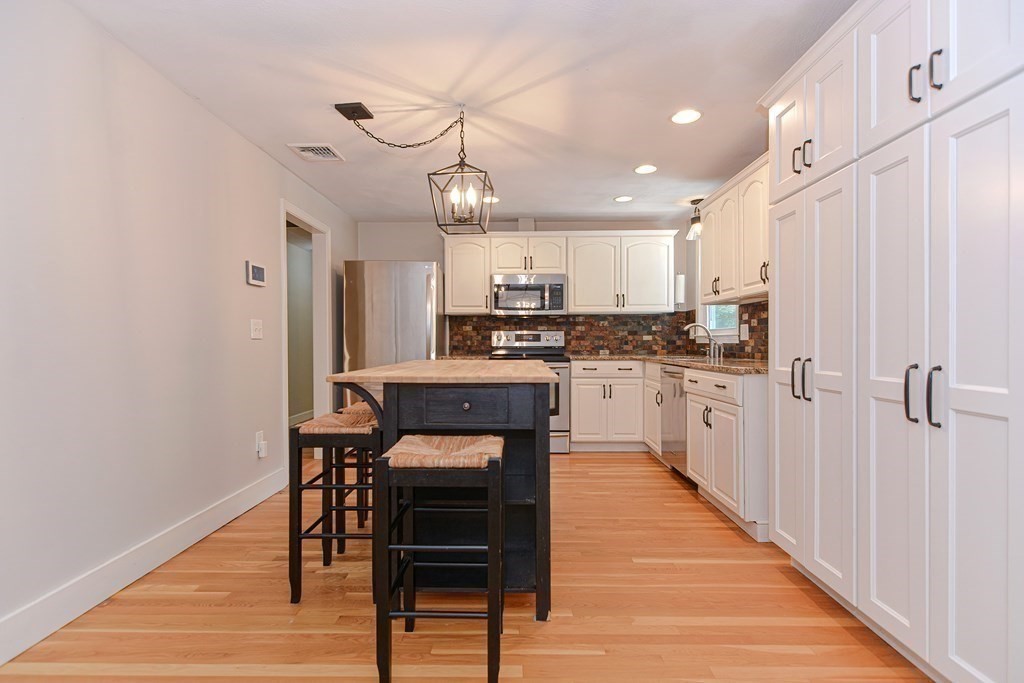 137 Howard Street Northborough, MA 01532 - Photo 10 of 41 a kitchen with kitchen island granite countertop wooden floors and white cabinets