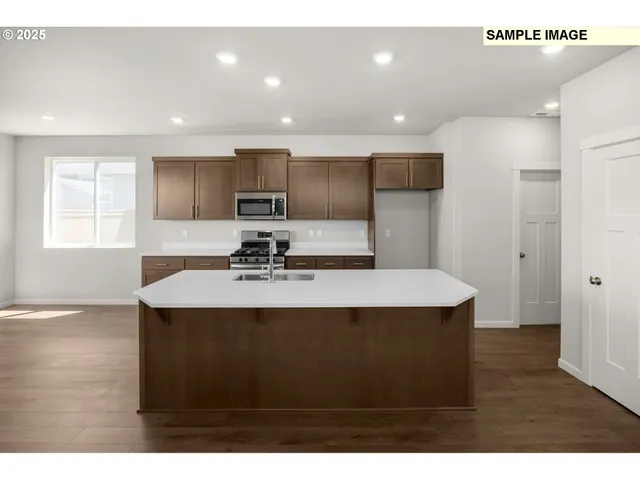 a view of kitchen with kitchen island a sink dishwasher a stove a refrigerator with wooden cabinets and floor