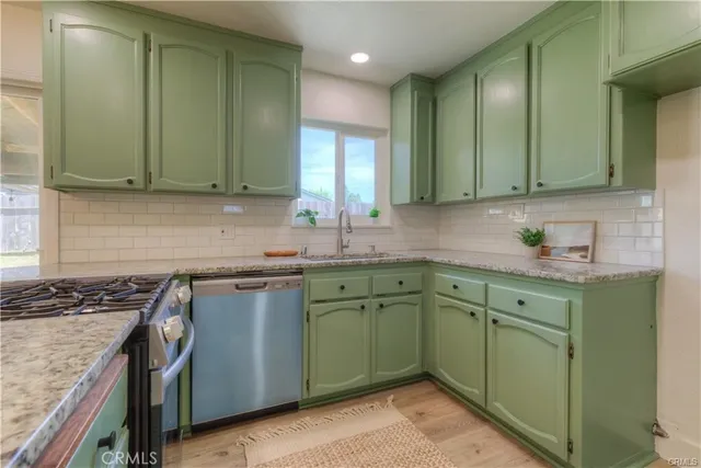 a kitchen with granite countertop a sink a stove and cabinets