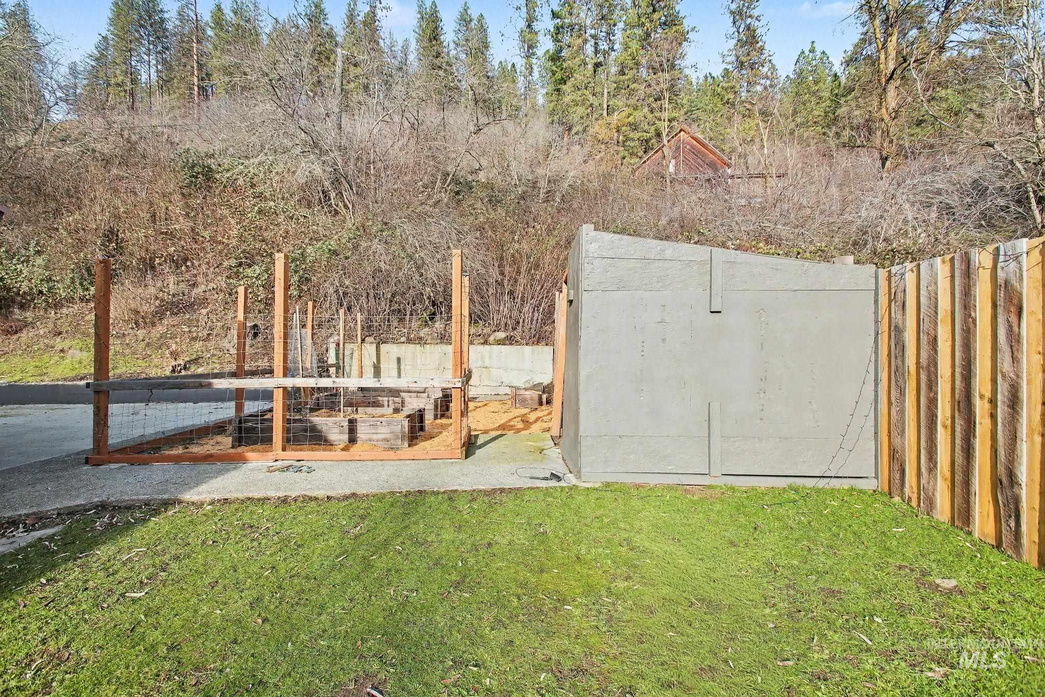 150 Elm Street Orofino, ID 83544 - Photo 30 of 36 Gated outdoor enclosure with wooden raised garden beds, gravel ground cover, and a solid wood privacy fence