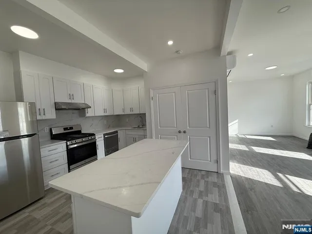 a kitchen with a refrigerator a stove top oven and white cabinets with wooden floor