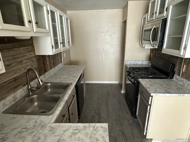 a kitchen with granite countertop a sink a stove and refrigerator
