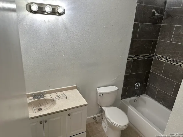 a white toilet sitting next to a bathroom sink and a mirror