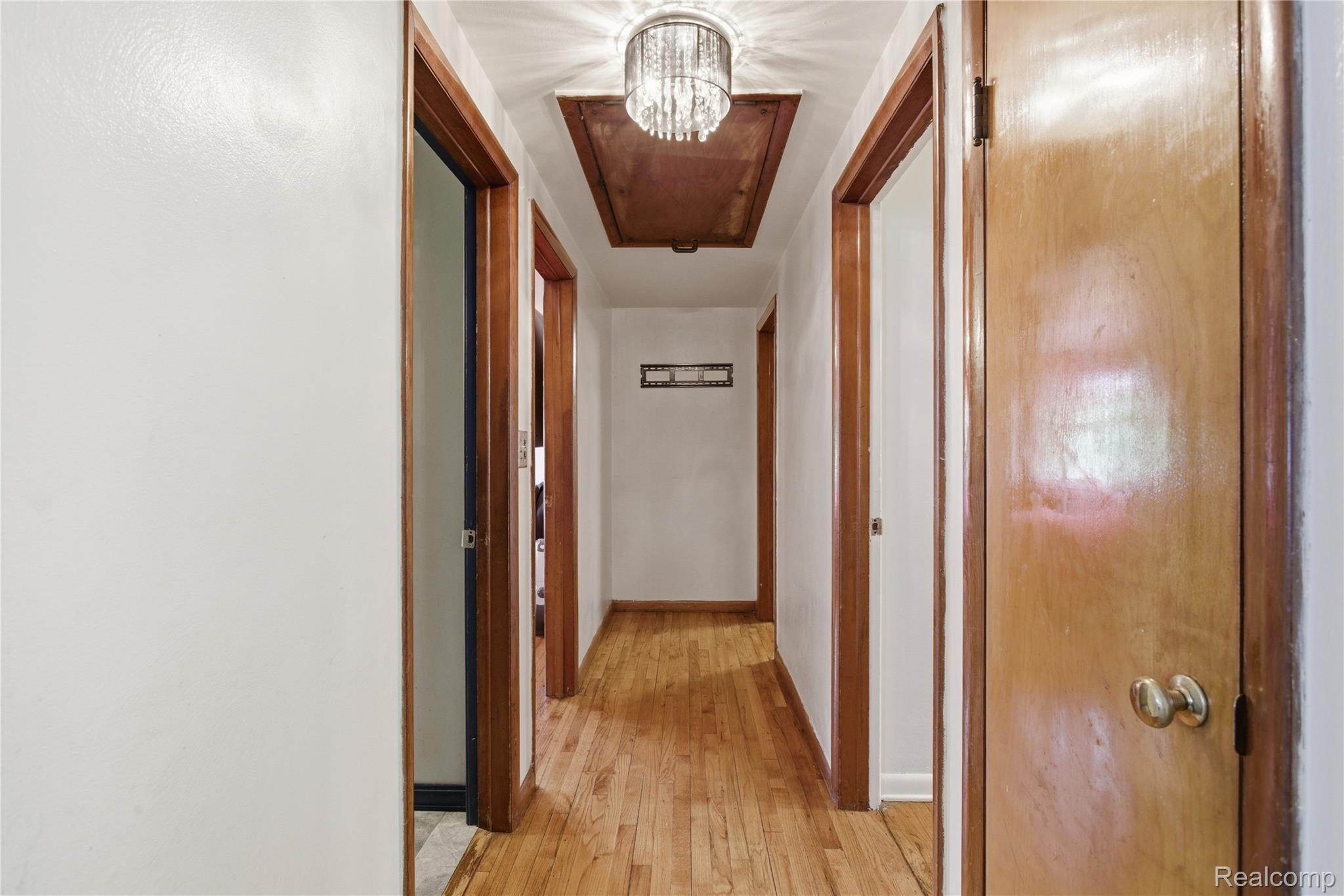 2705 Glendale Road Jackson, MI 49203 - Photo 25 of 57 Hallway featuring wood-finish flooring, white walls, and multiple paneled doors with wood-finish trim