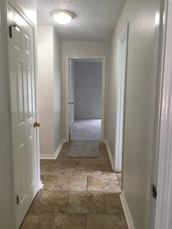 a view of a hallway with wooden floor and a bathroom