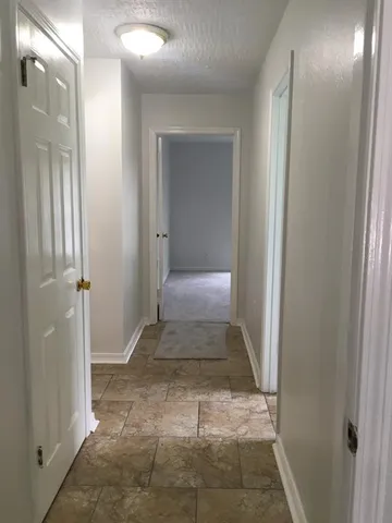 a view of a hallway with wooden floor and a bathroom