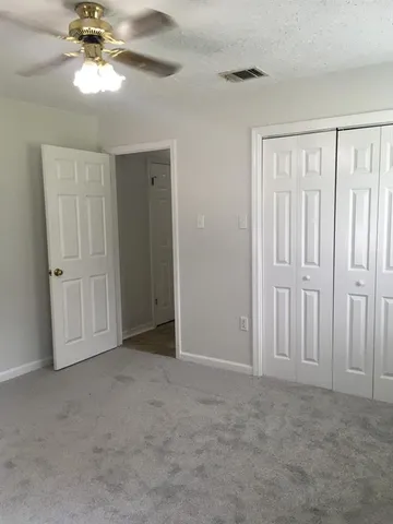 a view of an empty room and chandelier fan