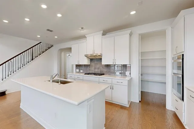 a kitchen with a sink stainless steel appliances and white cabinets