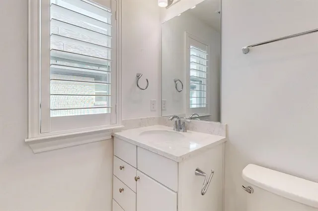 a bathroom with a sink toilet vanity and window