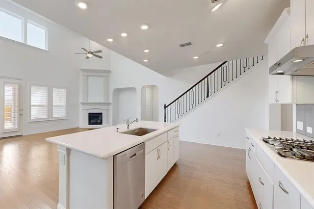 a kitchen with stove a sink and dishwasher with wooden floor
