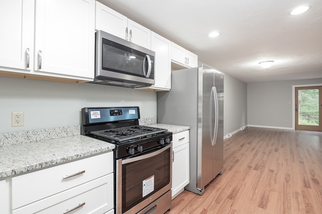 4 Shellback Way, Unit A4 Mashpee, MA 02649 - Photo 8 of 30 a kitchen with stainless steel appliances granite countertop a stove a sink and a microwave