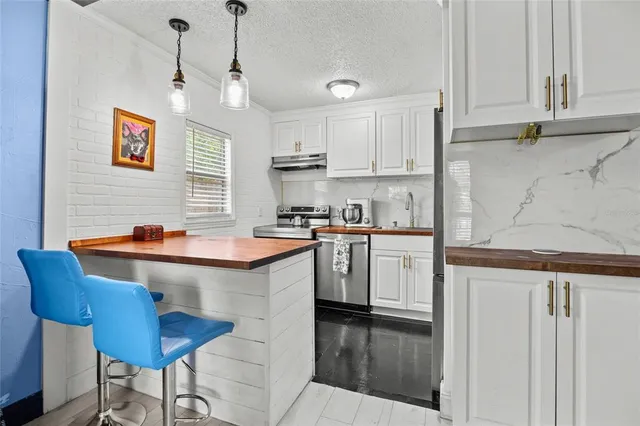 a kitchen with stainless steel appliances granite countertop a sink a stove and a refrigerator