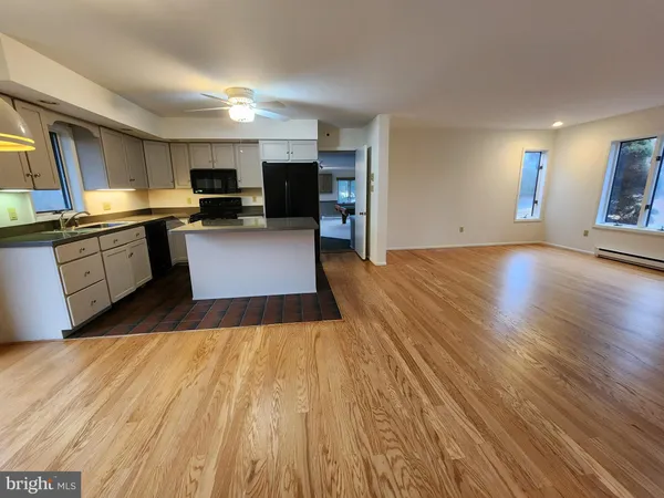 a kitchen with stainless steel appliances granite countertop a refrigerator oven a sink dishwasher and white cabinets with wooden floor