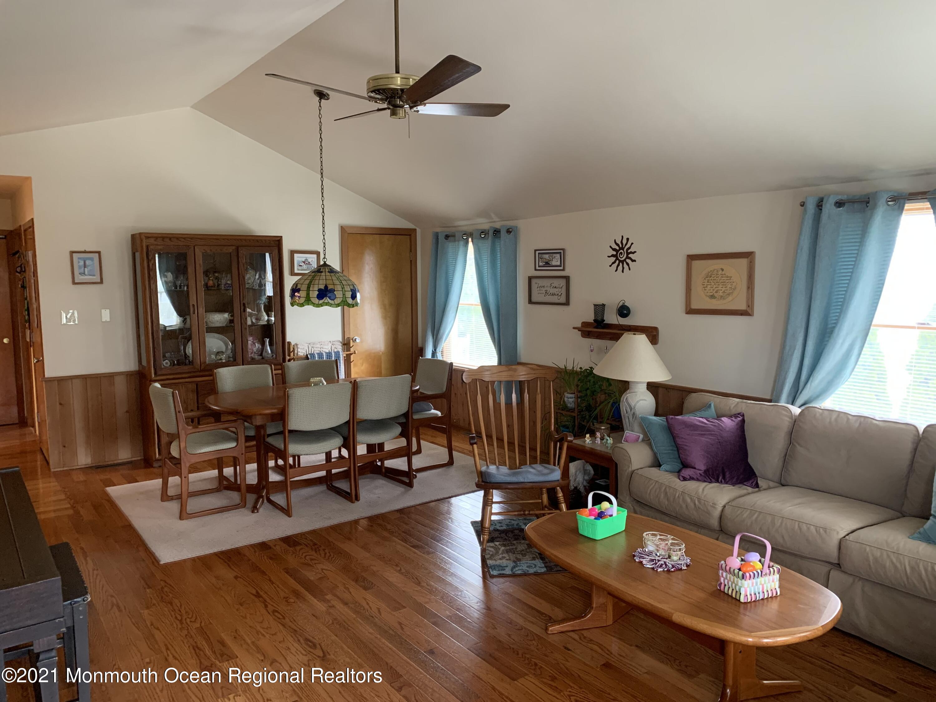 105 Seaspray Road Manahawkin, NJ 08050 - Photo 11 of 25 a living room with furniture and a dining table with wooden floor