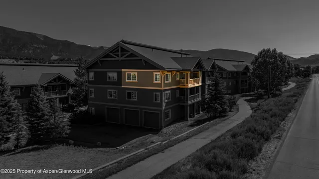 a view of a house with a small yard and large trees