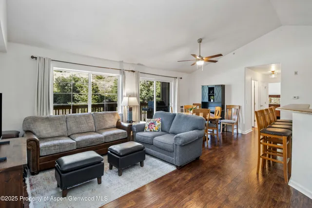 a living room with furniture two large windows a fireplace and a chandelier