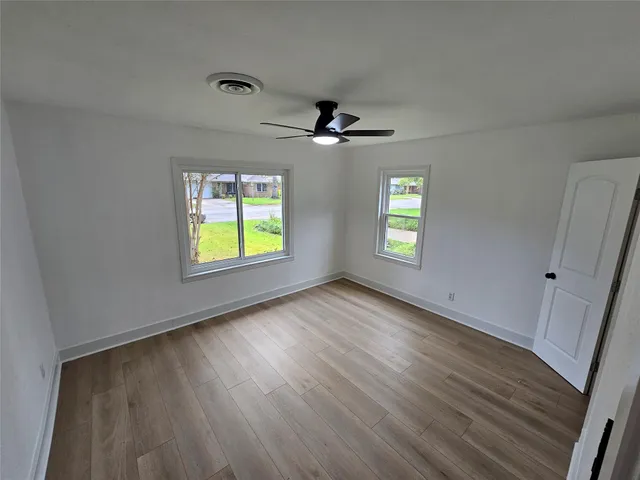 a view of an empty room with window and wooden floor